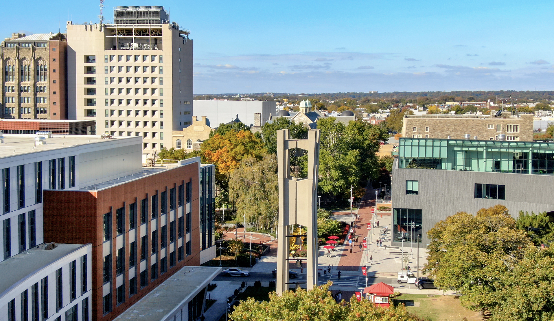 A view of the new Paley Hall and the bell tower on Main Campus. The sky is a bright blue and the trees are green.